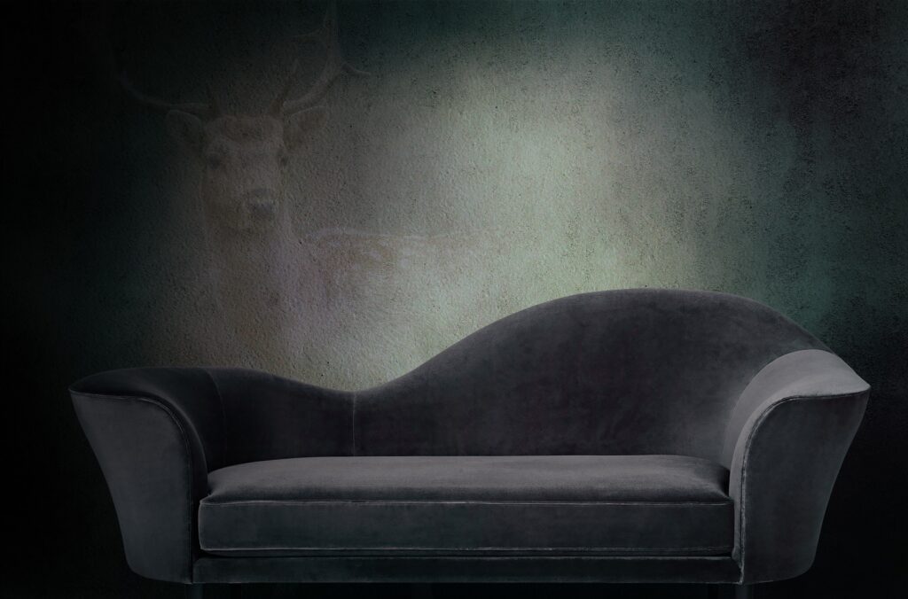 Donkergrijze chaise longue tegen een donkere maar mooi belichte achtergrond